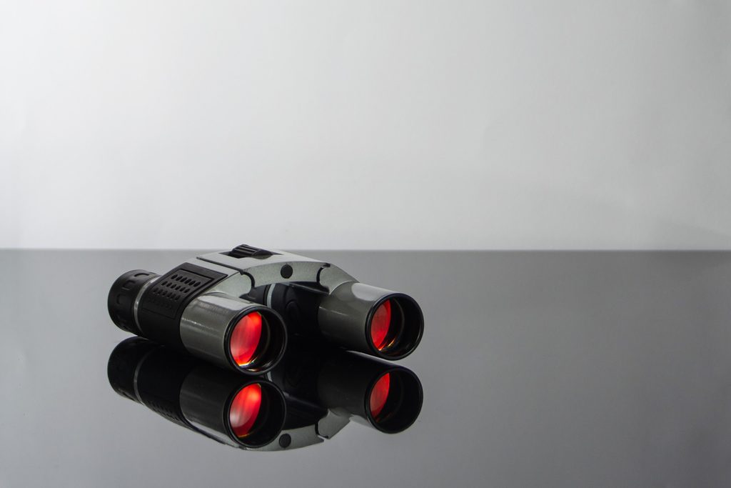 Black and grey binoculars with a red lens.